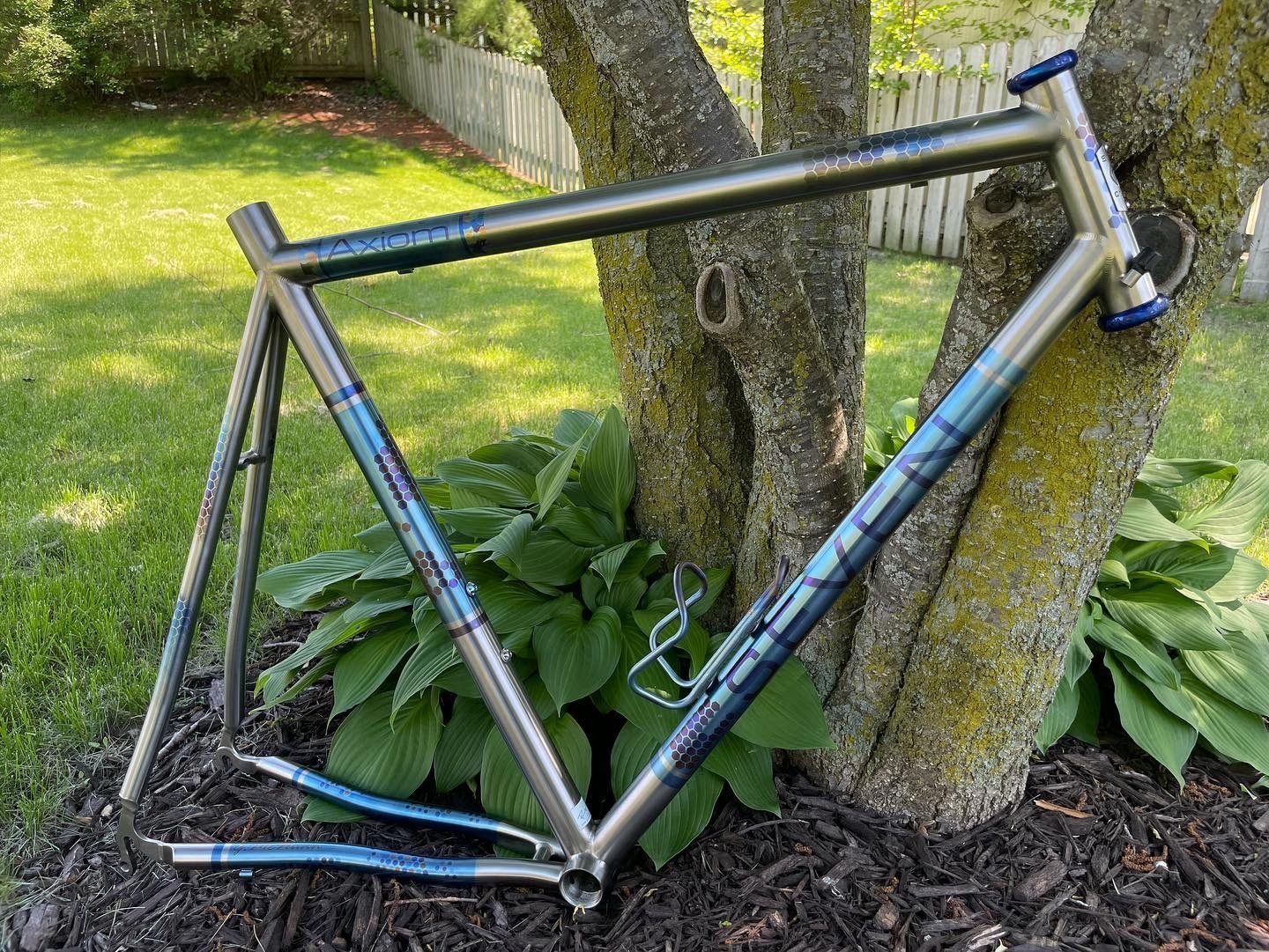 Ti-dye speckle anodized frame leaning against a tree