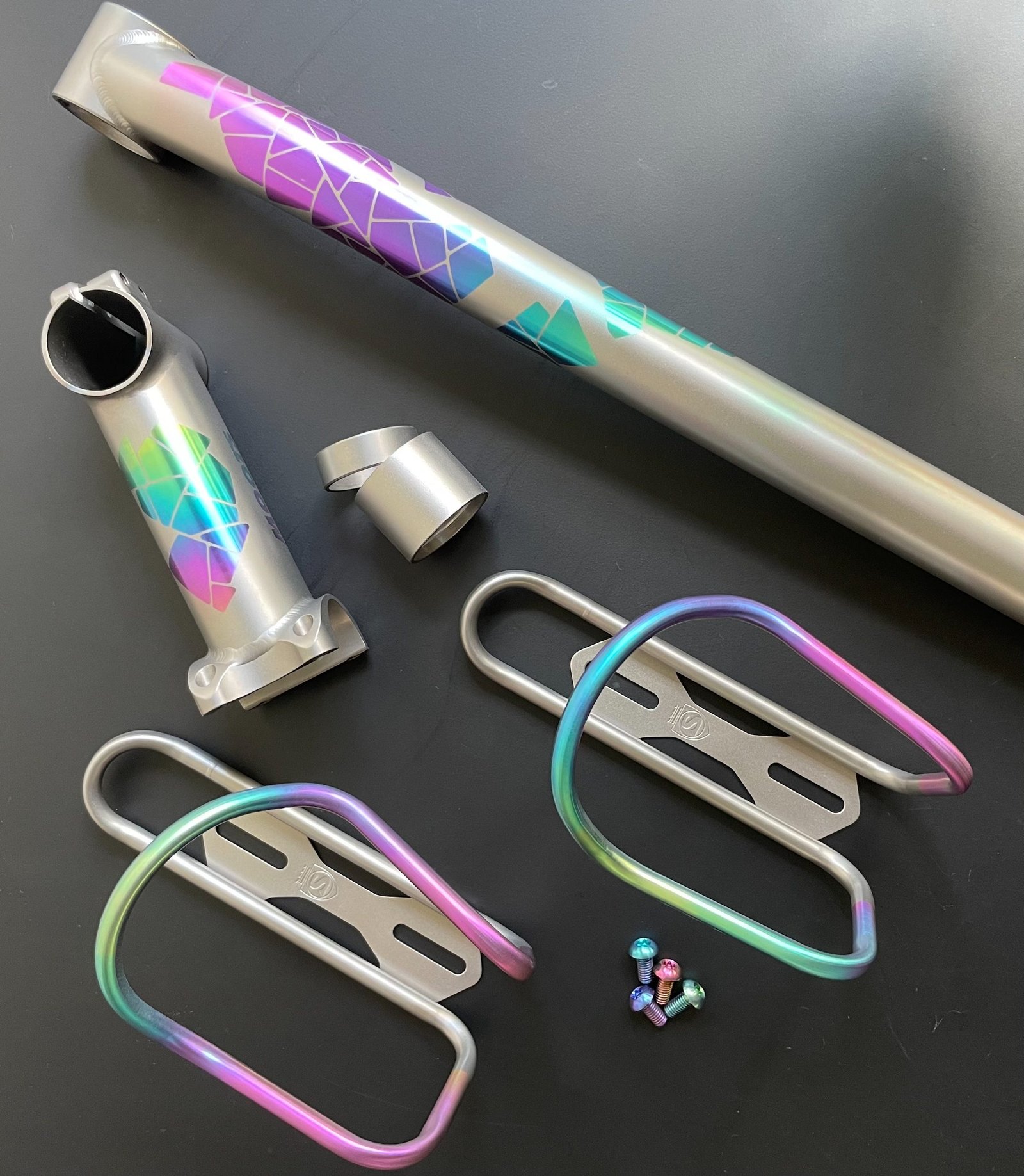 Anodized titanium tube, stem and matching bottle cages laid out together