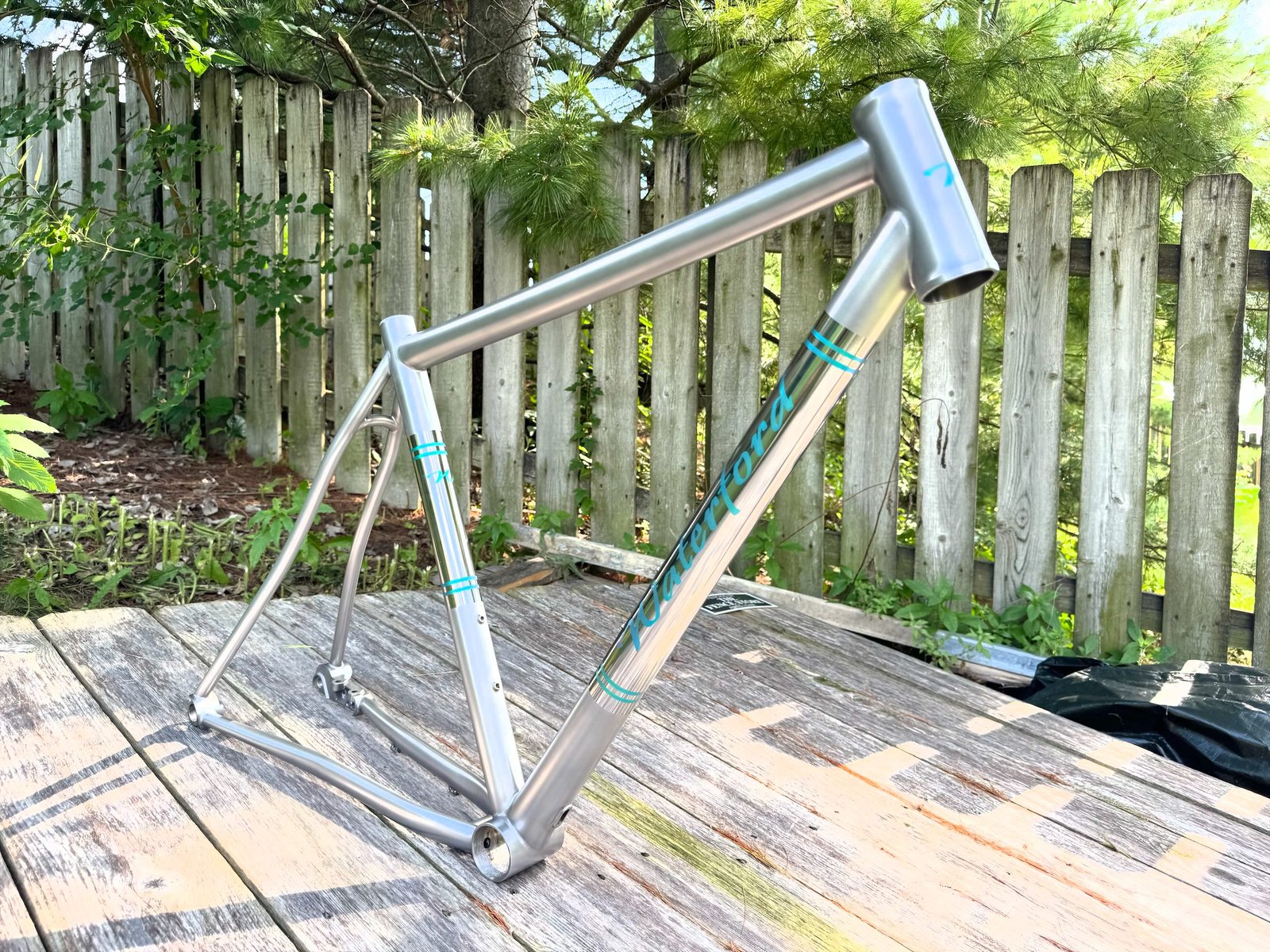 Raw titanium frame with teal anodized accents on a deck