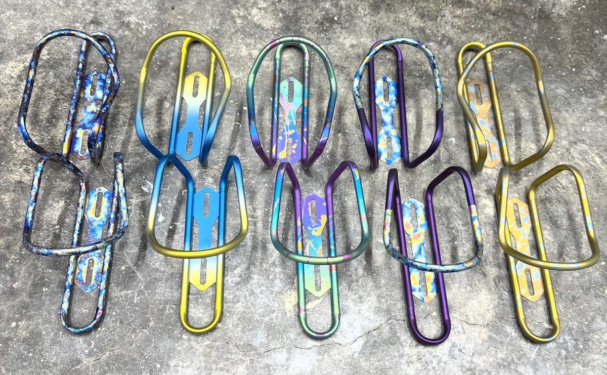 Ten anodized titanium bottle cages in a range of custom colours